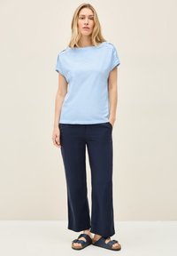 Top azul claro de manga corta combinado con pantalones de pierna ancha en marino. El top tiene un escote redondo y un corte relajado; los pantalones tienen una textura suave.
