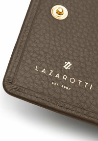 Copertina per quaderno in pelle marrone con texture, dotata di accessori in oro e logo impresso, con la scritta "LAZAROTTI EST. 2007" in lettere maiuscole.