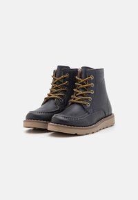Bottines en cuir marine avec des semelles en caoutchouc marron, des lacets jaunes contrastants, des coutures décoratives et un design à bout rond.