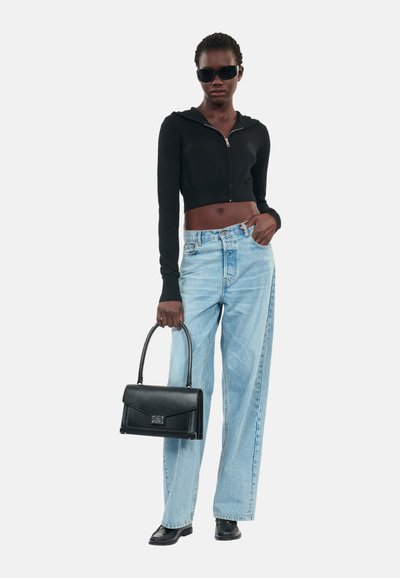 Felpa nera corta con zip frontale, jeans a gamba larga blu chiaro, borsa in pelle nera e occhiali da sole neri. Texture lisce in tutto.