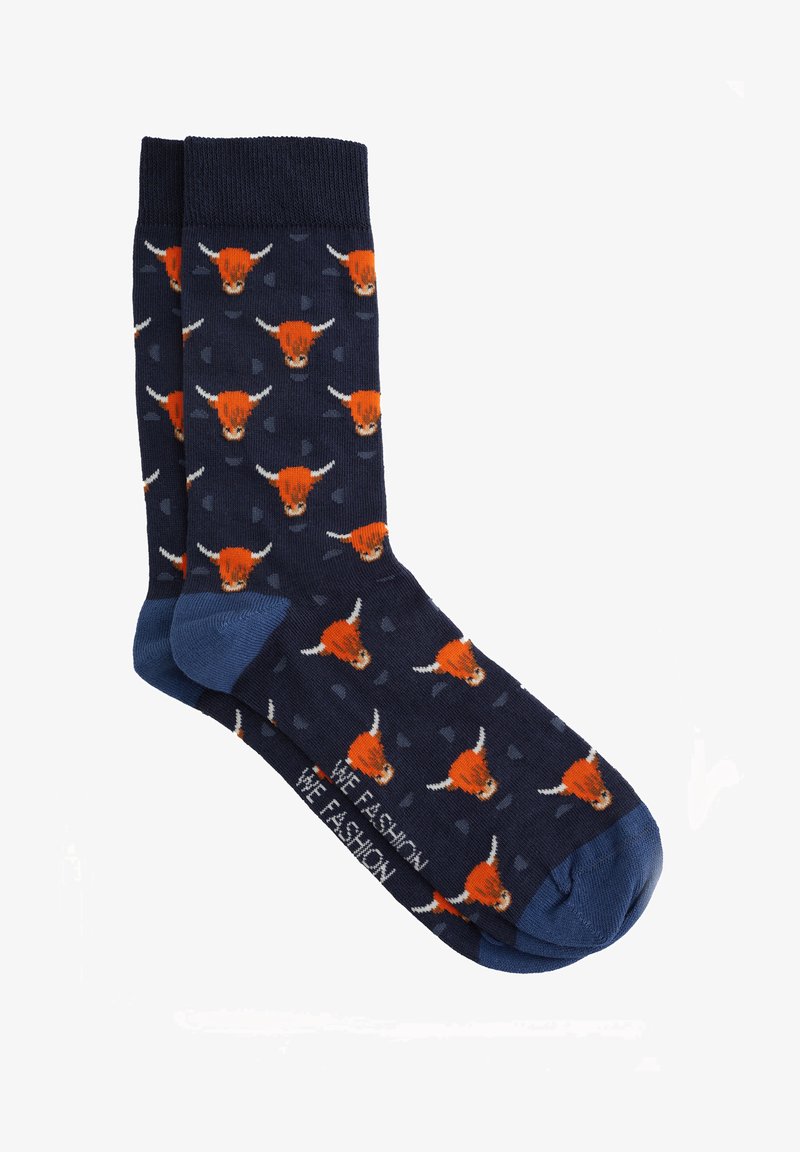 Jūras zilu zeķu, kurām ir zili papēži un pirksti, rotājumi ar atkārtojošiem oranžiem vērša galvām un mazām abstraktām formām.