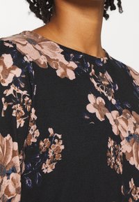 Czarna tkanina w kwiatowy wzór z dużymi różowymi i niebieskimi kwiatami, o gładkiej fakturze i klasycznym kroju z okrągłym dekoltem.