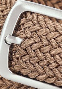 Spleciony pasek z tkaniny w jasnobrązowym kolorze z metalową klamrą w kolorze srebrnym, z teksturowanym, tkanym wzorem zapewniającym trwałość i elastyczność.