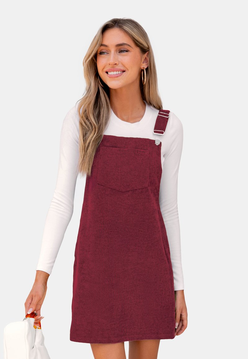 Bordeaux corduroy overall jurk met verstelbare bandjes, een voorzak en textiele stof, gecombineerd met een witte lange mouwen top.