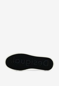 Sola di sneakers con una superficie in gomma nera testurizzata, caratterizzata da un motivo a zigzag e logo "Desigual" in rilievo. Bordo bianco attorno alla suola.