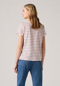 Striped short-sleeve T-shirt in soft pink with navy and white stripes; relaxed fit. Paired with high-waisted blue jeans.