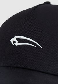Black cap made of textured fabric with a curved brim. Features a white stylized logo resembling a panther on the front.