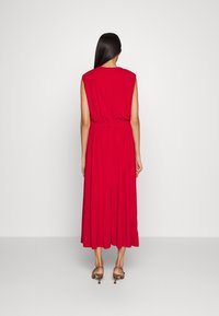 Czerwona sukienka bez rękawów z dopasowanym wcięciem w talii i swobodną spódnicą. Miękka tkanina, do kolan, czysty design, gładka faktura, proste zapięcie na plecach.