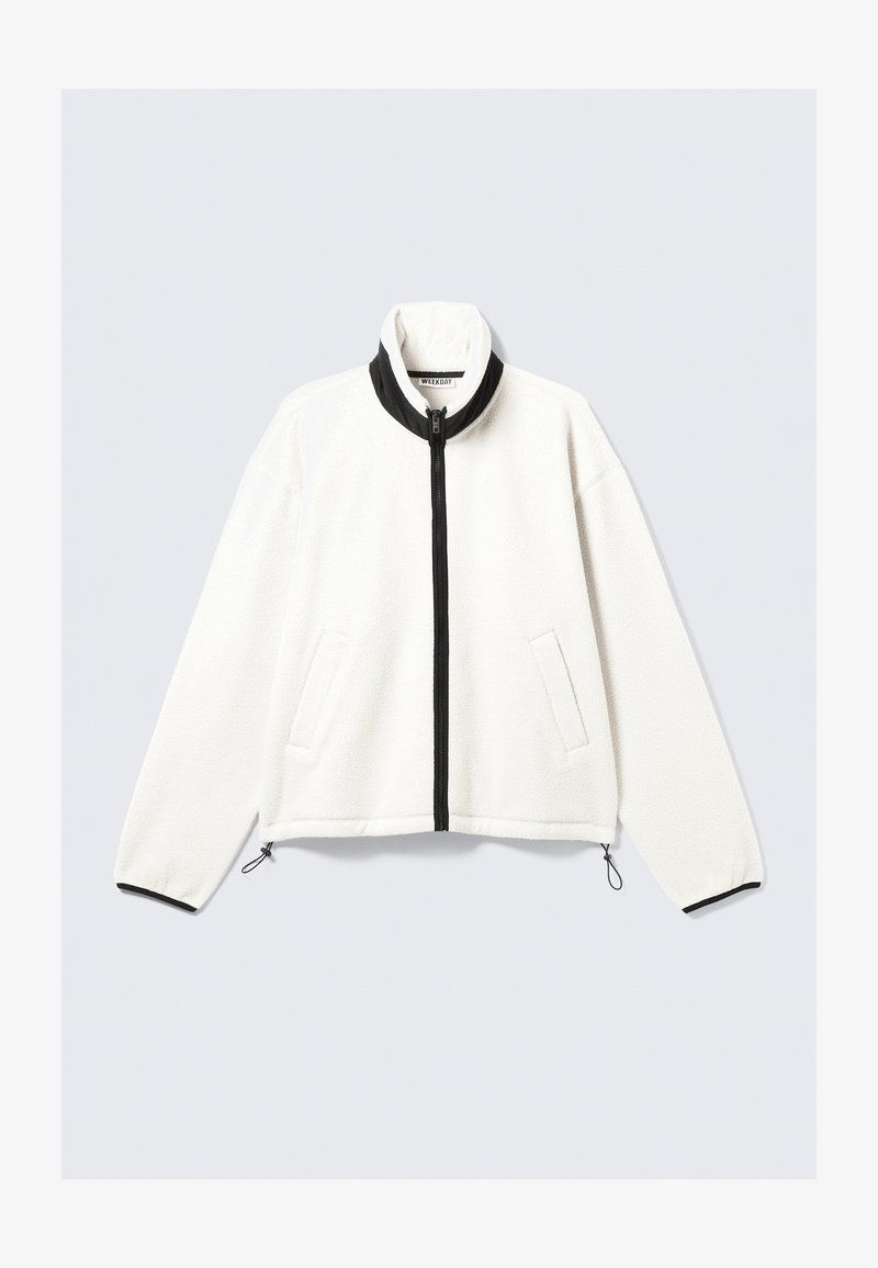 Λευκή φλις ζακέτα με μαύρο φερμουάρ μπροστά, ψηλό γιακά, δύο πλαϊνές τσέπες και ελαστικούς μανσέτες με ρυθμιζόμενους αυξομνητές στο στρίφωμα.