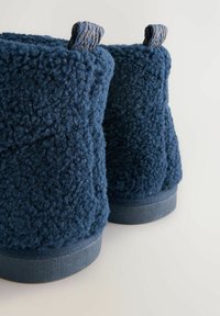 Stivaletti alla caviglia in tessuto blu scuro, strutturato, con superficie morbida e soffice e suole di gomma piatte. Presentano cinturini in tessuto ad anello per una facile calzata.