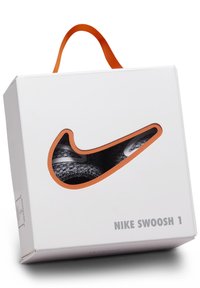 Caja de zapatos blanca con un mango naranja y diseño de Swoosh recortado. Contiene zapatos grises y negros en su interior. Texto: "NIKE SWOOSH 1."