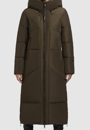 Long manteau d’hiver marron matelassé avec capuche, fermeture éclair devant et poches latérales, porté par une personne sur un fond uni.