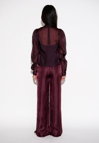 Bordeaux, doorschijnende blouse met pofmouwen, gecombineerd met bijpassende wijde broek. Glad weefsel, ritssluiting aan de achterkant en vloeiende silhouet.