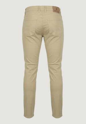 Beige slim-fit jeans gezien van achteren met twee achterzakken en een bruine leren merkembleem op de tailleband.
