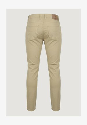 Beige slim-fit jeans gezien van achteren met twee achterzakken en een bruine leren merkembleem op de tailleband.