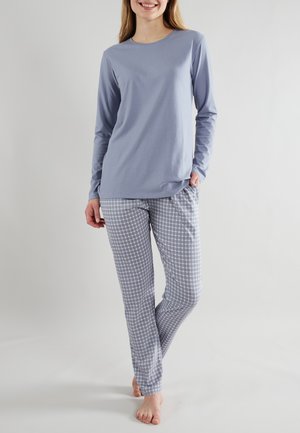 Helleblaue Langarmbluse kombiniert mit grauen und weißen karierten Schlafanzughosen. Baumwollstoff, lockere Passform und Taschen in den Hosen.