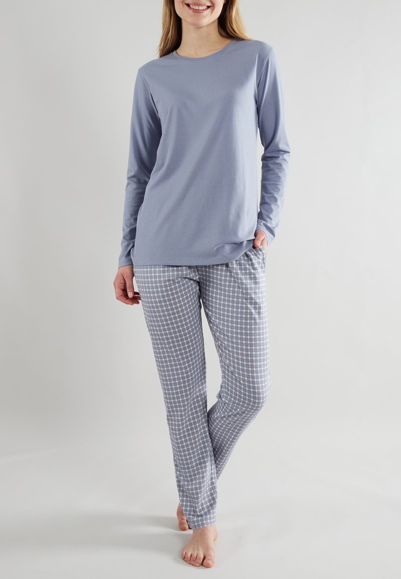 Maglia azzurro chiaro a maniche lunghe abbinata a pantaloni da pigiama a quadretti grigi e bianchi. Tessuto di cotone, vestibilità comoda e tasche nei pantaloni.