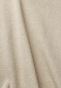 Tessuto intrecciato beige con una consistenza morbida, caratterizzato da una superficie liscia e leggermente elastica, con variazioni di ombra sottili.