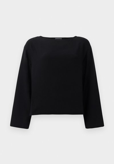 Musta pitkähihaisen paita, jossa on pyöreä kaula-aukko, valmistettu sileästä kankaasta. Muotoilu on lyhennetty ja suora helman kohdalla. Minimalistinen tyyli.