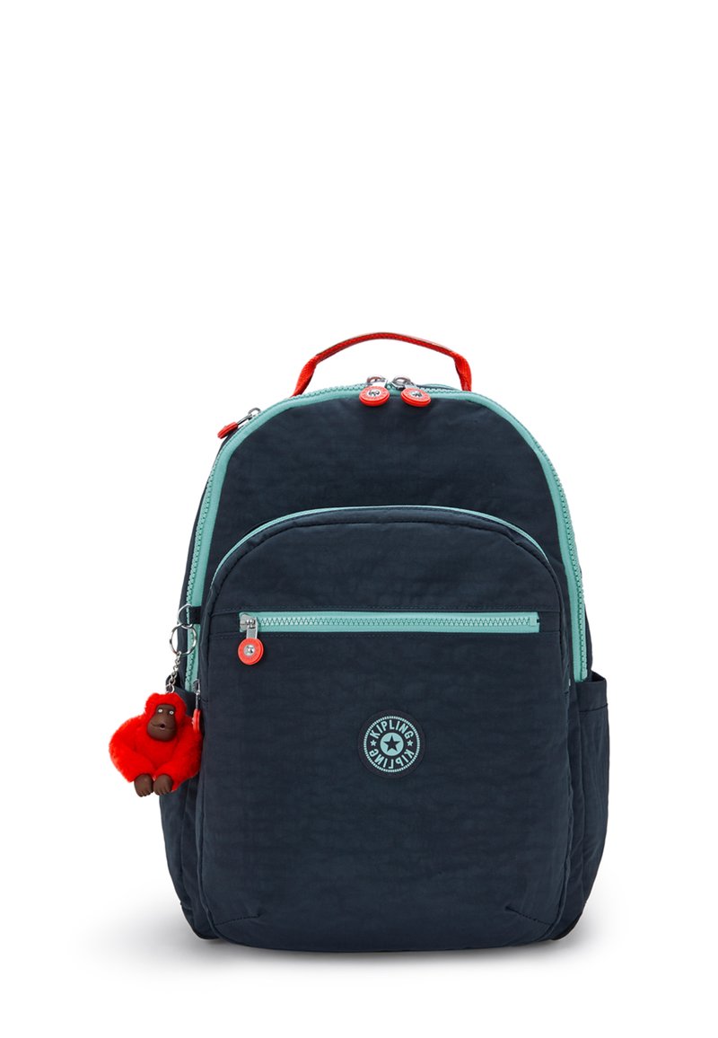 Tmavěmodrý batoh s texturovaným povrchem, mátově zeleným zipem, červenými akcenty a podivným klíčenkou ve tvaru opice. Obsahuje několik kapsiček a pevnou rukojeť.