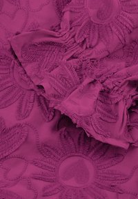 Fuchsia stof met dichte bloemen- en hartborduursels. Geweven oppervlak met franjes aan de randen en gelaagde ontwerpdetails. Lichtgewicht materiaal.