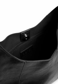 Juodas odinis rankinės vidus, kuriame matyti užtrauktukas ir magnetinė uždanga su audiniu išklota.