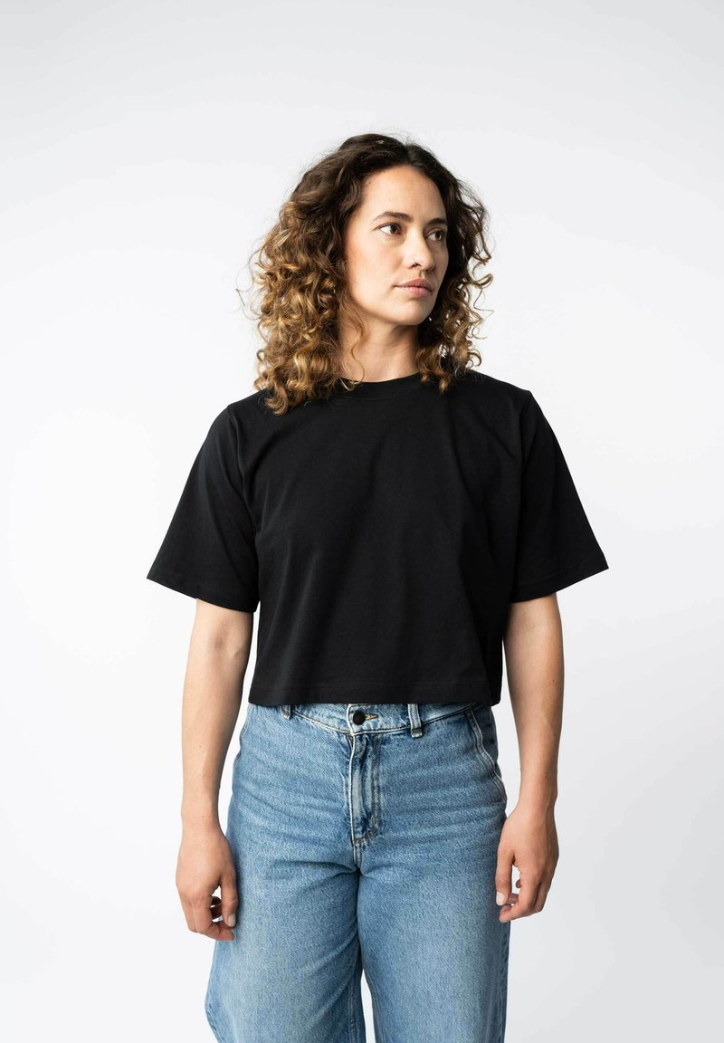 Zwarte cropped t-shirt van katoen met korte mouwen, ronde halslijn en een ontspannen pasvorm, gecombineerd met hoge taille blauwe jeans.