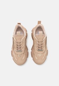 Baskets beige avec une surface texturée, des panneaux en maille, des lacets et un talon renforcé. Dotées d'une languette à l'arrière pour un enfilage facile.
