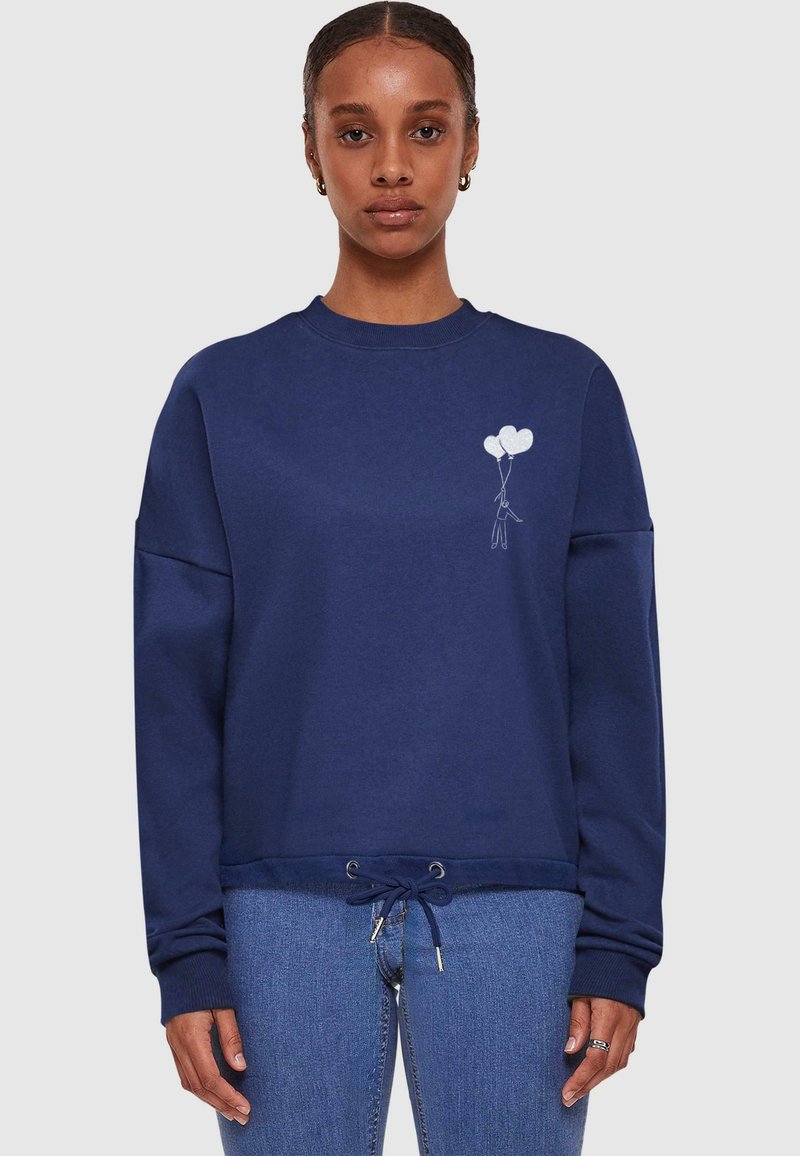 Felpa blu navy con collo a giro, spalle abbassate e orlo con cordino elastico. Presenta una grafica di un palloncino bianco sul petto.