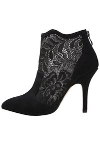 Stivale ankle in suede nero con punta affusolata, pannelli laterali in pizzo floreale a rete e tacco alto sottile con chiusura a zip sul retro.
