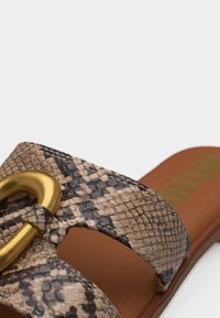 Sandale à enfiler avec semelle marron, bride à motif peau de serpent et grand détail boucle dorée sur la partie supérieure.
