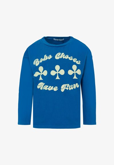 Blaues langärmeliges T-Shirt aus Baumwolle mit cremefarbenem Schriftzug "Bobo Choses Have Fun" und Kleeblattmotiven auf der Vorderseite. Rippenkragen.