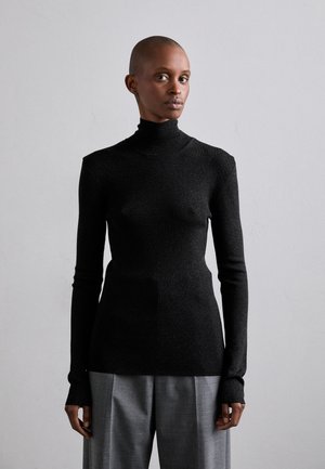 Mustra mustriga mustre pikkade varrukatega must turtleneck-sviiter. Valmistatud tekstuurist, sädelevast kangast. Kombineeritud hallide kohandatud pükstega.