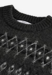 Dark gray knit sweater featuring a ribbed neckline. It has a white geometric pattern with diamonds and dots, creating a textured appearance.