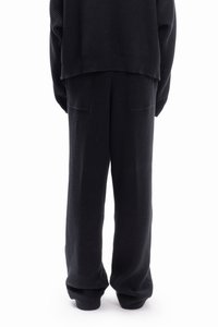 Knitted black sweater and pants set, featuring a relaxed fit, ribbed cuffs, and side pockets on the pants, showcasing a soft texture.