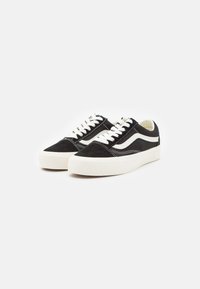 Zapatillas de ante negras con detalles en blanco, que presentan un diseño estampado, punta redonda, suela gruesa blanca y cierre clásico de cordones.