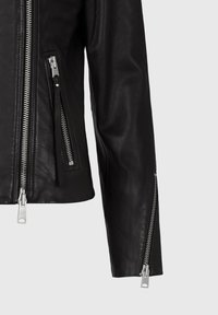 Svart lädermotorcykeljacka med silverfärgade dragkedjor, med två framfickor och dragkedjor på ärmarna för extra detalj och stil.