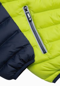 Veste matelassée avec une manche gauche bleu marine et un corps vert lime vif, dotée d'une fermeture zippée et d'accents gris.