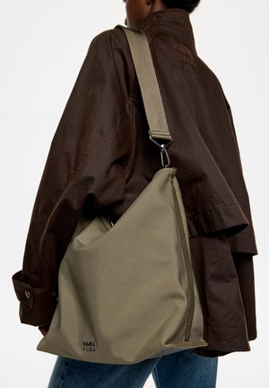 Bolso de hombro verde olivo hecho de tela suave, con cierre de cremallera, correa ajustable y detalle de logo en relieve.