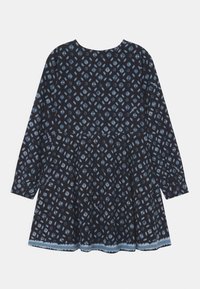 Dlouhé rukávy tmavě modré šaty s světle modrým geometrickým diamantovým vzorem a mírně rozšířenou sukní, na bílém pozadí.