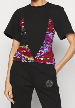 Haut noir à manches courtes avec un panneau froncé à motif multicolore à l'avant, présentant des designs floraux et une coupe géométrique.