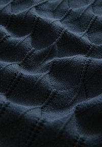 Tissu tricoté bleu marine avec un motif en losange texturé, présentant des arêtes et des détails en ajouré, créant un effet tridimensionnel.
