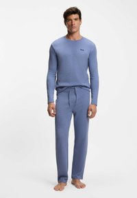 Light blue loungewear set made of textured fabric, featuring a long-sleeve top and drawstring pants, with a discreet logo on the chest.