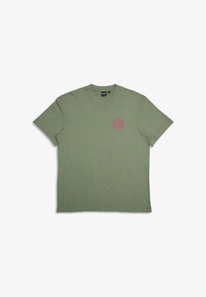 Camiseta de algodón verde oliva con mangas cortas. Presenta un logo rojo redondo en el lado izquierdo del pecho. Textura suave, cuello redondo clásico.