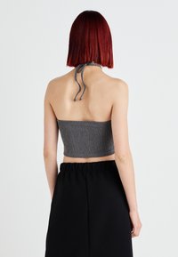 Γκρι ριγωτό κοντό τοπ με δέσιμο στον λαιμό, με υφή που ξεχωρίζει. Μαύρη φούστα ψηλόμεση ορατή από κάτω.