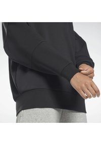 Schwarzer Sweatshirt mit lockerer Passform, gerippten Bündchen und Saum. Weiche Textur, mit schlichtem Design ohne Muster. Kombiniert mit grauen Jogginghosen.