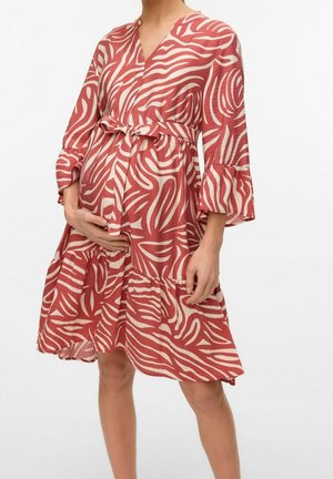 Sukienka w kolorze rdzy z białymi falistymi wzorami, dekolt w serek, z pasa podkreślonego paskiem oraz rozkloszowanymi rękawami. Wykonana z lekkiego materiału o warstwowej konstrukcji.