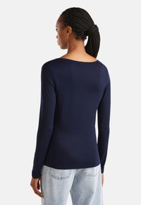 Granatowa koszula z długim rękawem z okrągłym dekoltem, wykonana z gładkiego materiału. Dopasowany krój z minimalną ilością szwów i miękką teksturą.