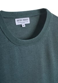 Suéter verde bosque hecho de una mezcla de lana, con un cuello redondo acanalado y textura suave. La etiqueta dice "ANTONY MORATO," tamaño M. Corte regular.