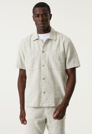 Lichtgrijs overhemd met korte mouwen gemaakt van gestructureerd linnen, voorzien van een knoopsluiting aan de voorkant en twee borstzakken. Minimalistisch ontwerp met subtiele stikselpatronen.